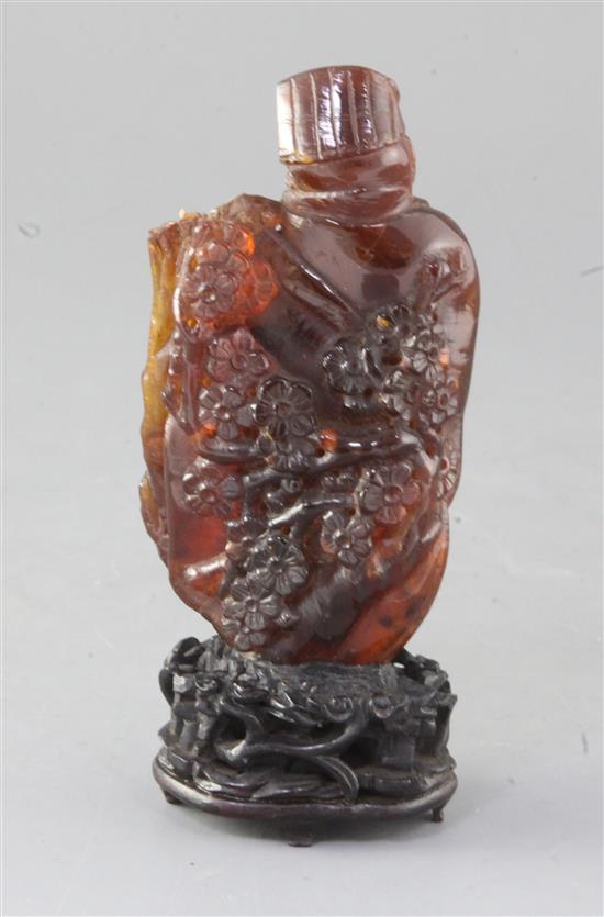 A Chinese amber group of a sage and a boy, Qing dynasty, attached to a wood stand, losses